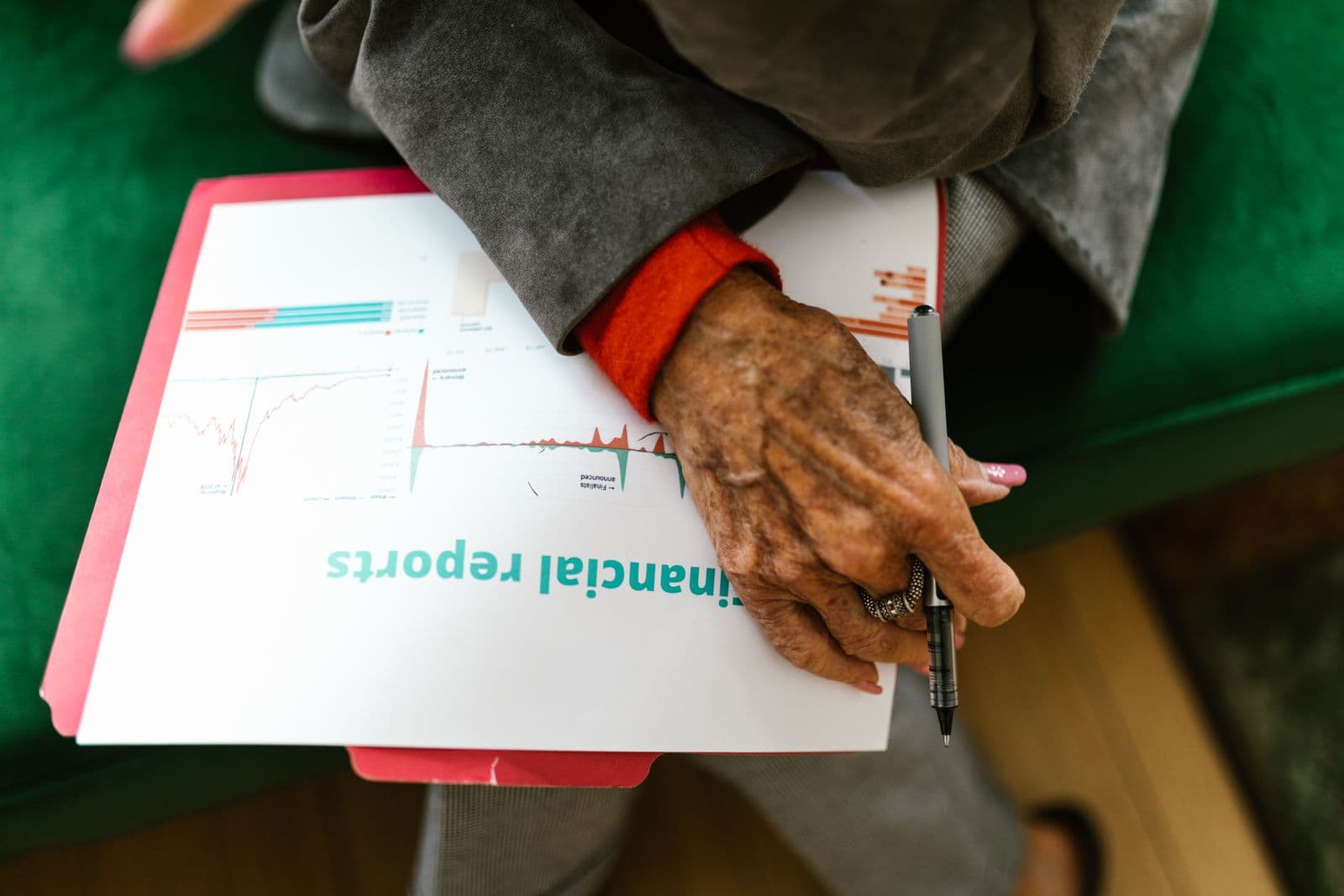 Une main tient un stylo au-dessus d'un rapport financier imprimé