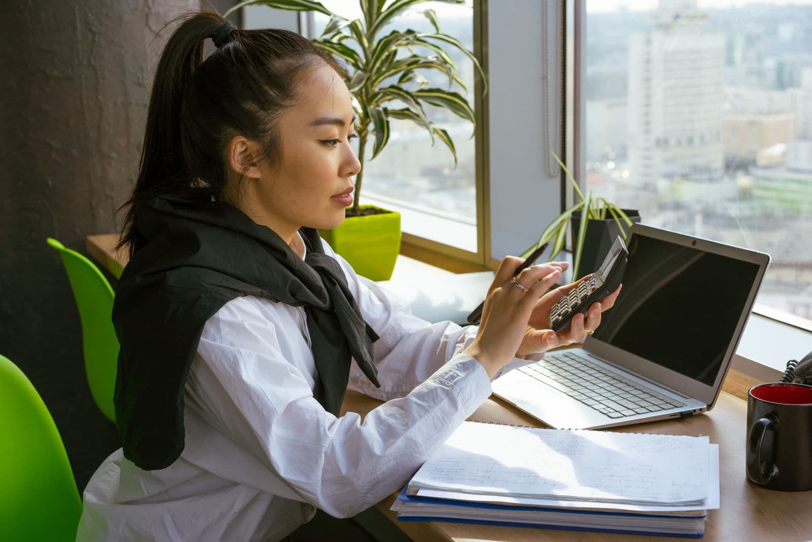 Une comptable vérifie des chiffres à la calculatrice devant son ordinateur