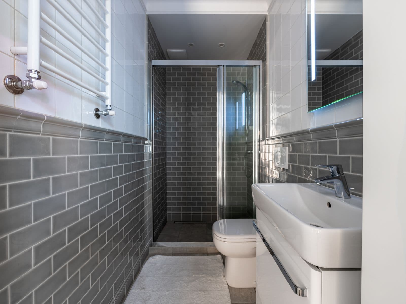 Salle de bain moderne entièrement carrelée de faïence grise, avec douche à l'italienne
