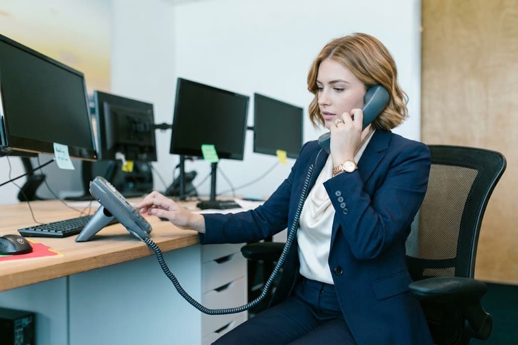 Une assistante prend un appel sur un poste téléphonique de bureau