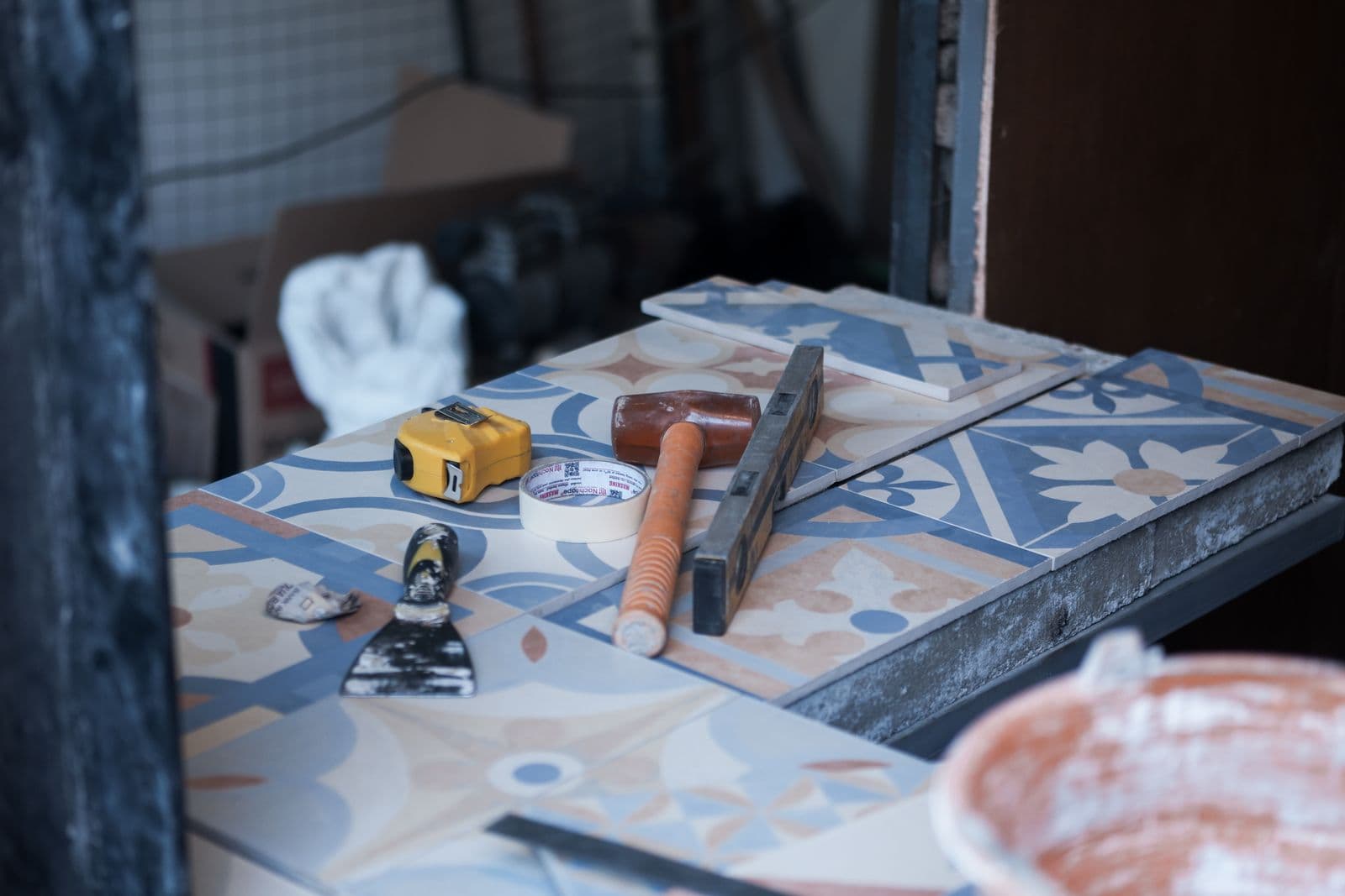 Carreaux à motifs et outils de carreleur (mètre, niveau, maillet et spatule) posés sur un établi