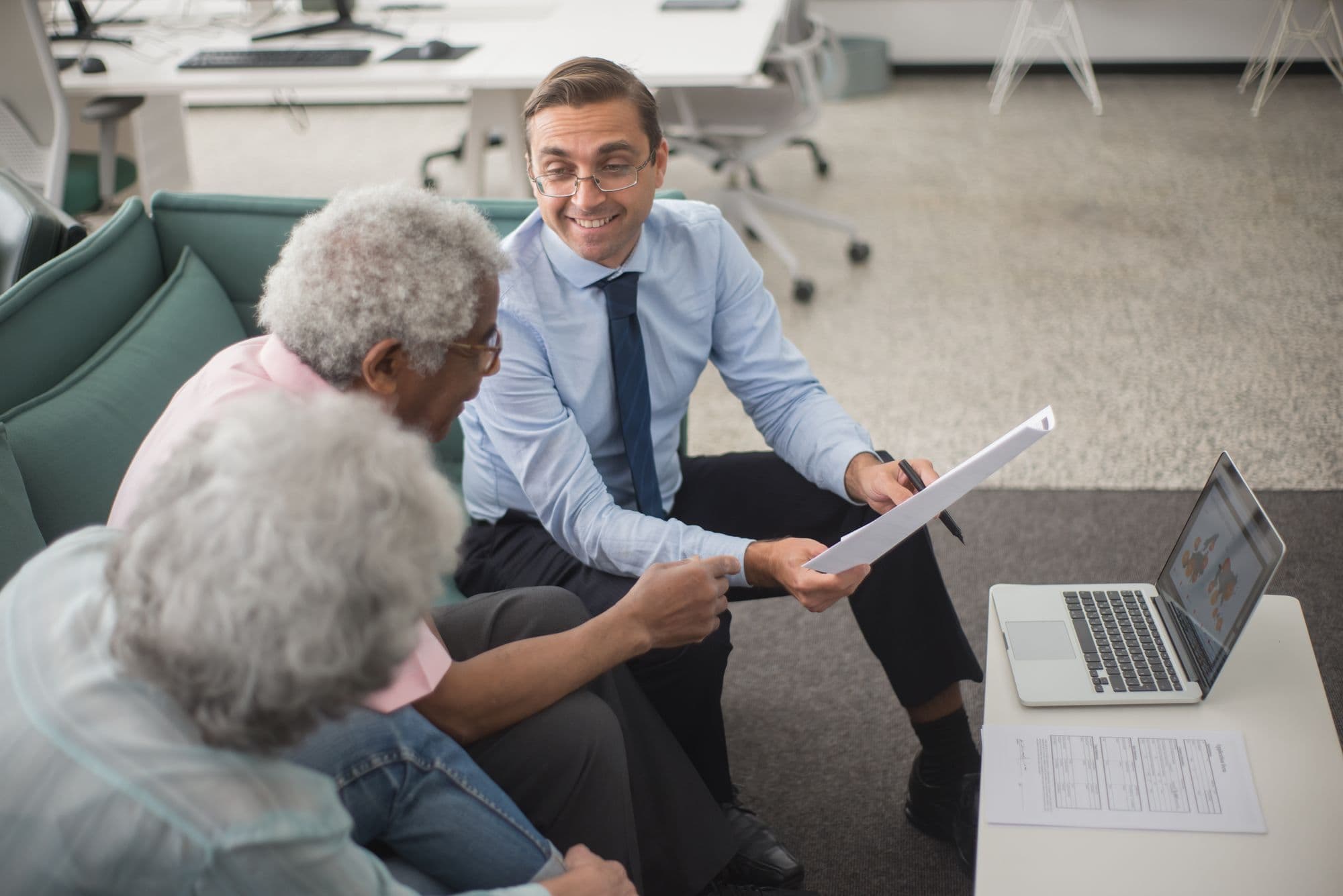 Un conseiller en assurance présente un contrat à un couple de clients dans un bureau