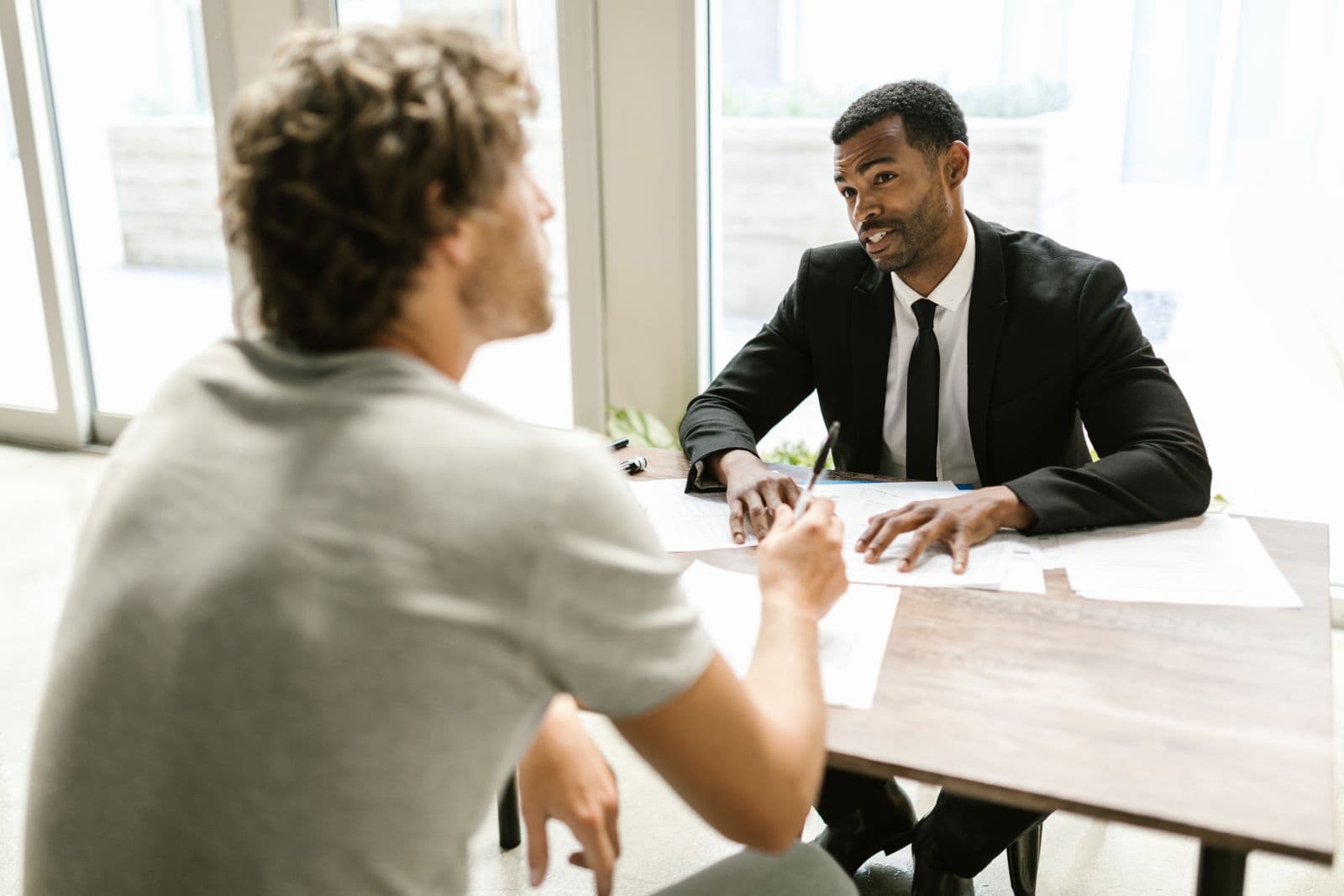 Un conseiller en costume échange avec un client au-dessus de documents