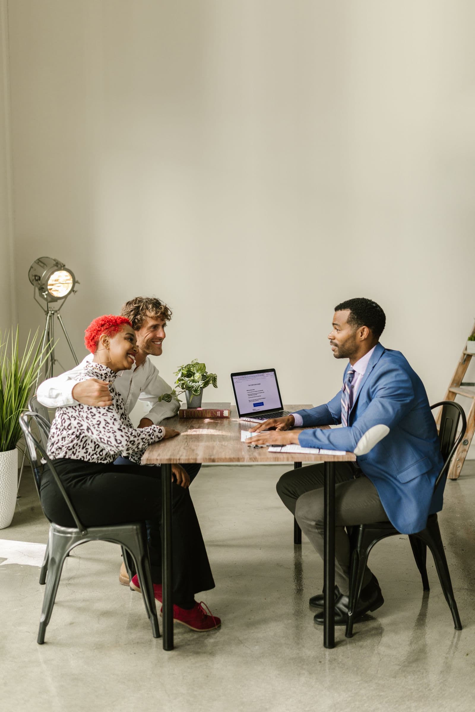 Un couple échange avec un conseiller autour d'un ordinateur portable