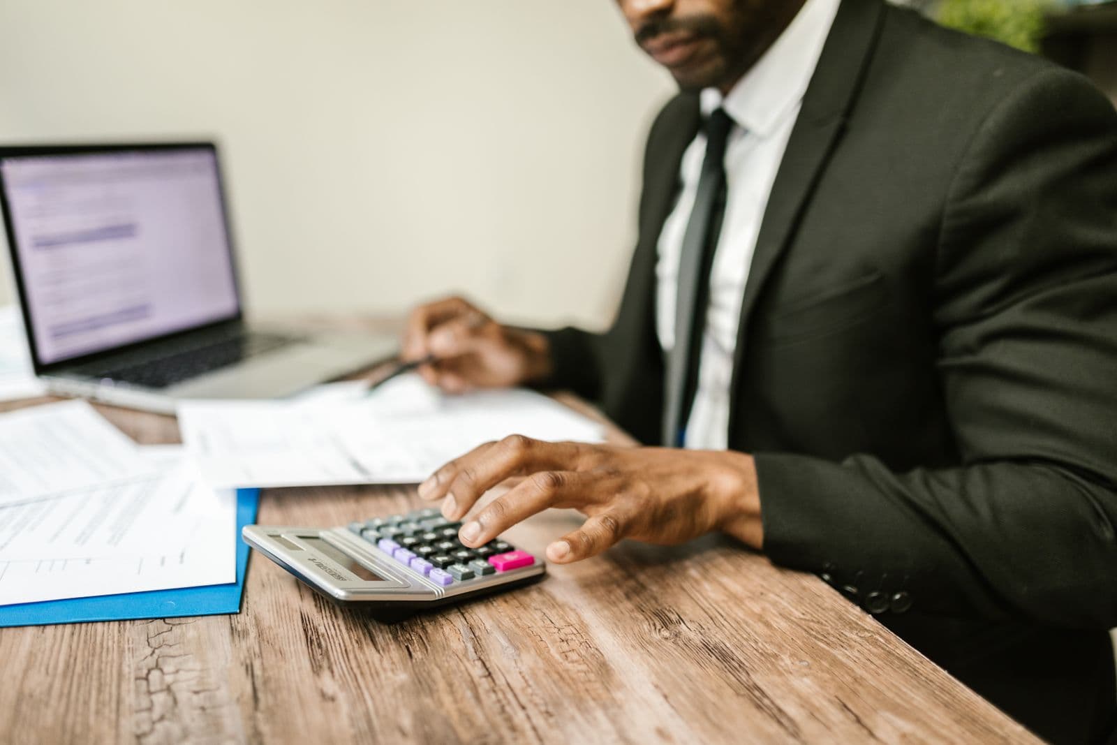Un expert-comptable en costume utilise une calculatrice à son bureau