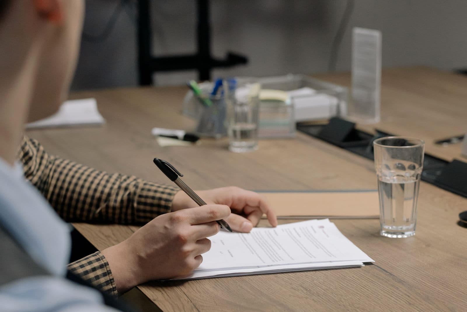 Une personne signe un document au stylo, sur une table de réunion