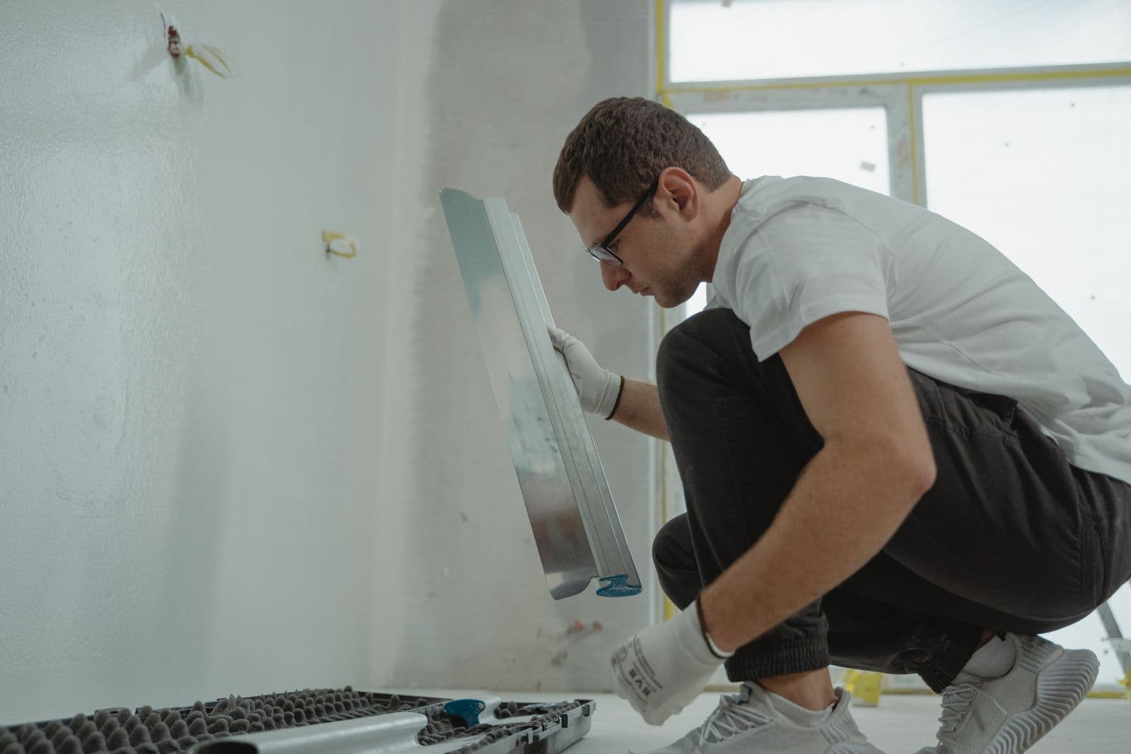 Un artisan prépare et lisse un mur à la spatule avant la pose du revêtement