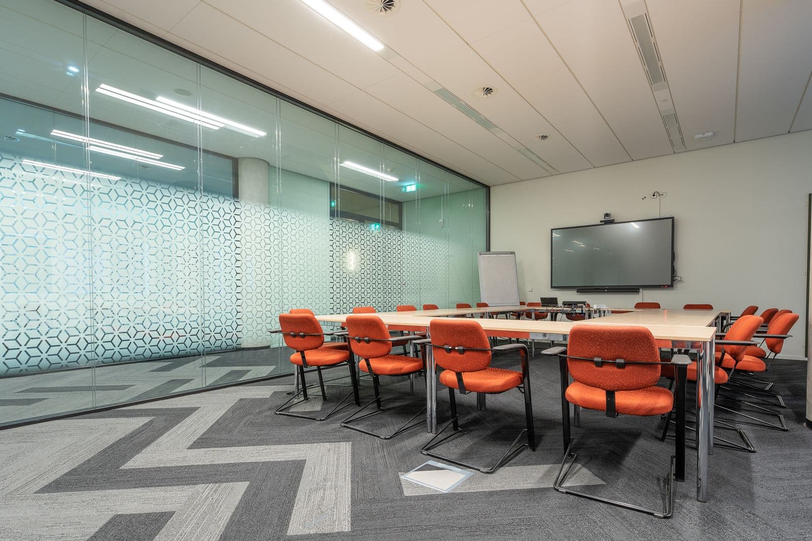 Salle de réunion moderne aux fauteuils orange, parois vitrées